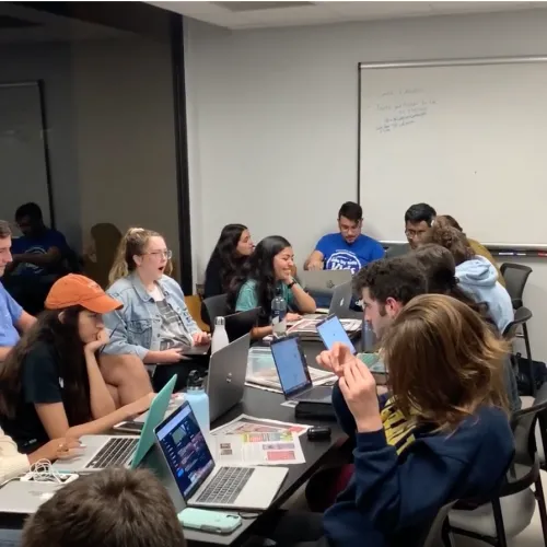 group of students working on computers around table