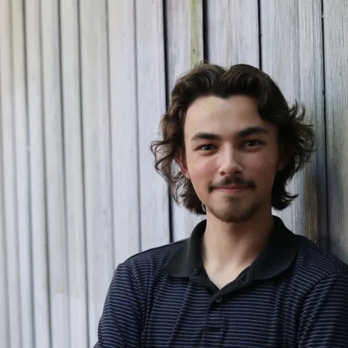 A young man with dark hair and a mustache