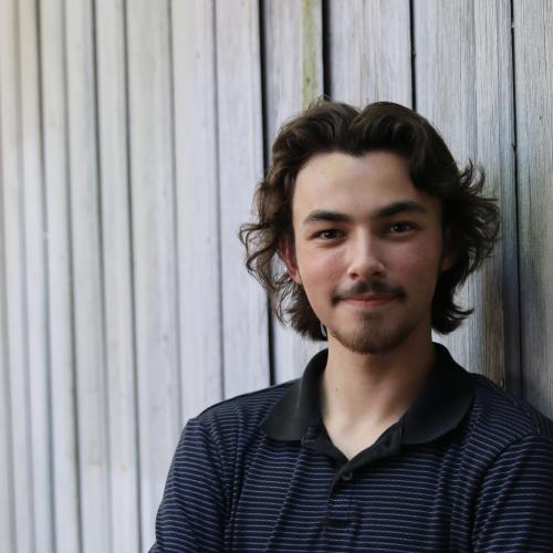 A young man with dark hair and a mustache