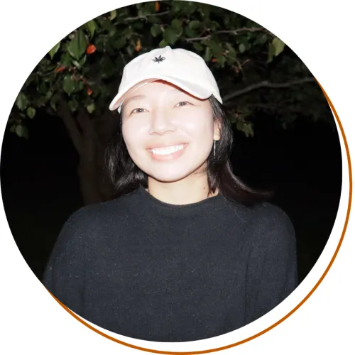 Yuqi Sun Headshot Yuqi Sun Headshot, black shirt and pink hat at nighttime, tree in the background