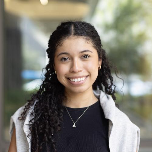A portrait of a. young woman with curly dark hair.