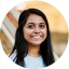 Headshot of Sanjana Ravi, a woman smiling with long dark hair in a pale blue t-shirt.