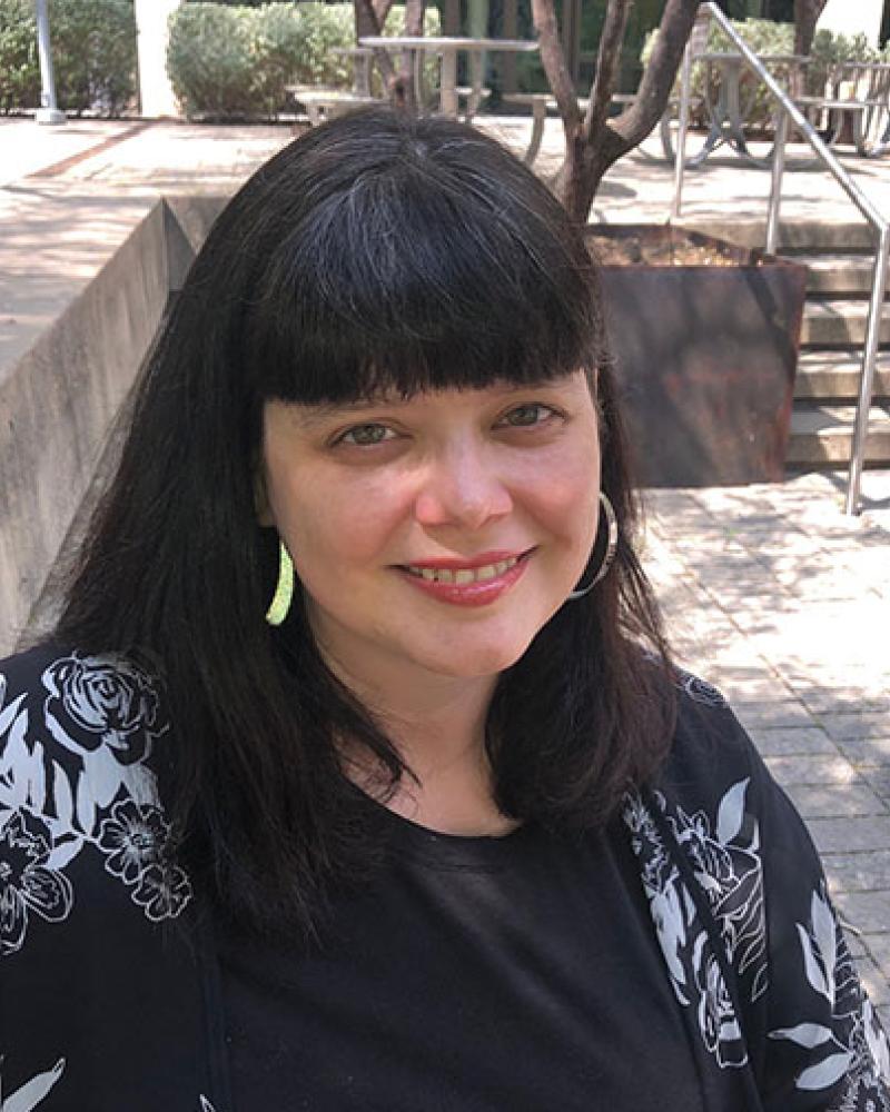 An older woman with dark hair and silver earrings