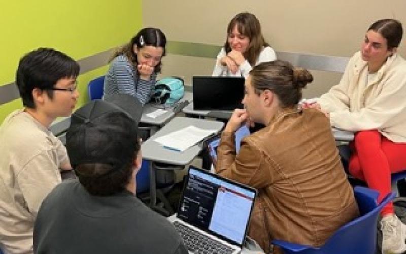 Six students sit in a circle to collaborate