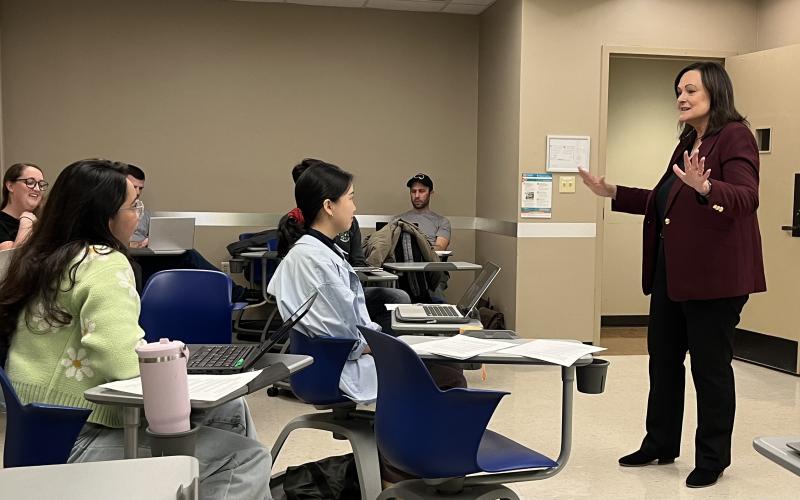 Dr. Stephens speaking animatedly with her hands as smiling students listen