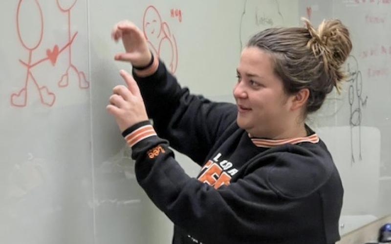 Student drawing a heart on a classroom whiteboard