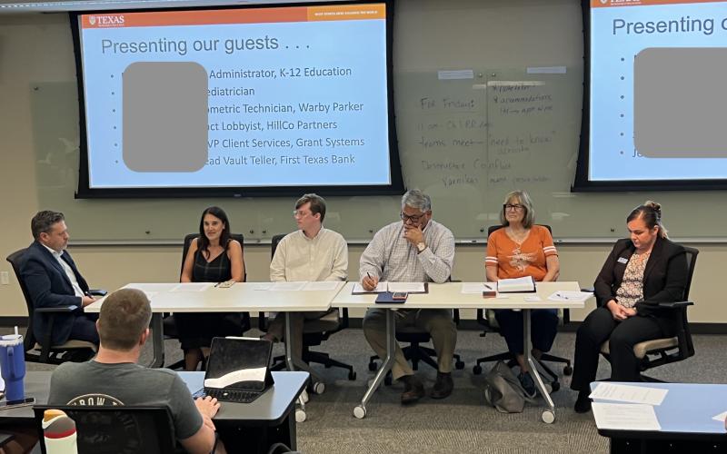 Image depicts a panel of speakers