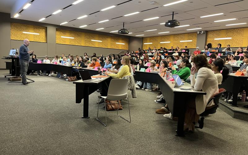 Professor Quigley addresses a large lecture hall of students. 