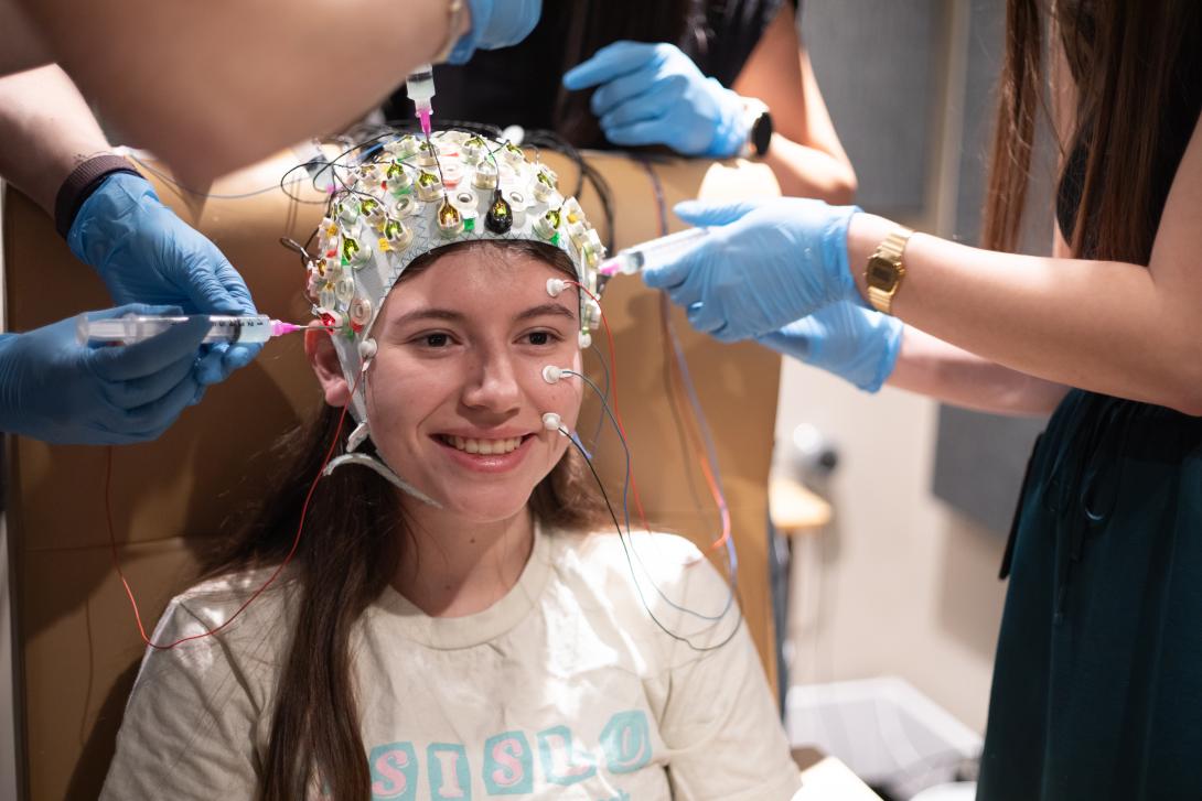 research patient wears cap to study eegs with hands putting gel on the cap